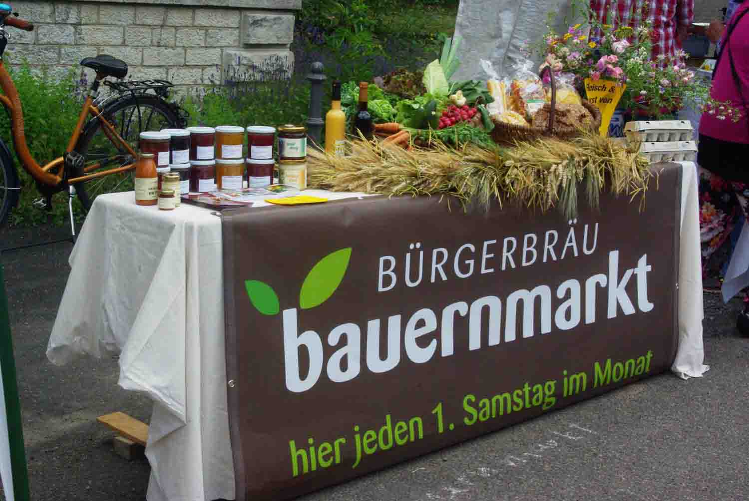 Bauernmarkt im Bürgerbräu September 2021 Tisch mit Banner und Dekoration mit Produkten der Beschicker