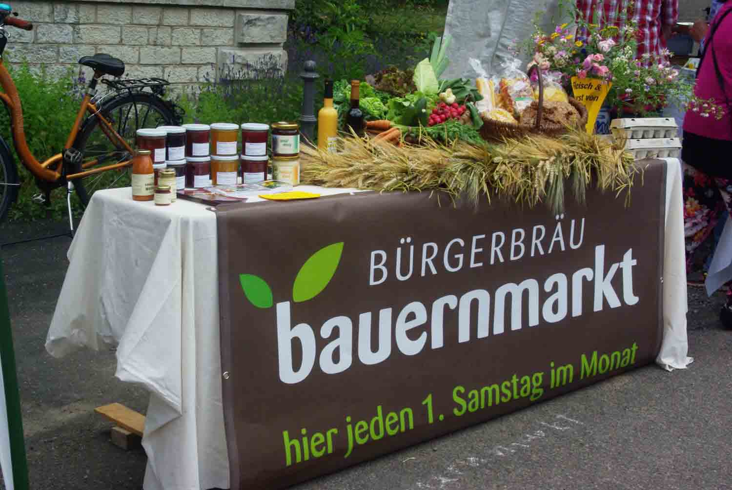 Tisch mit Banner mit der Aufschrift Bauernmarkt im Bürgerbräu Würzburg, dekoriert mit Waren der Beschicker